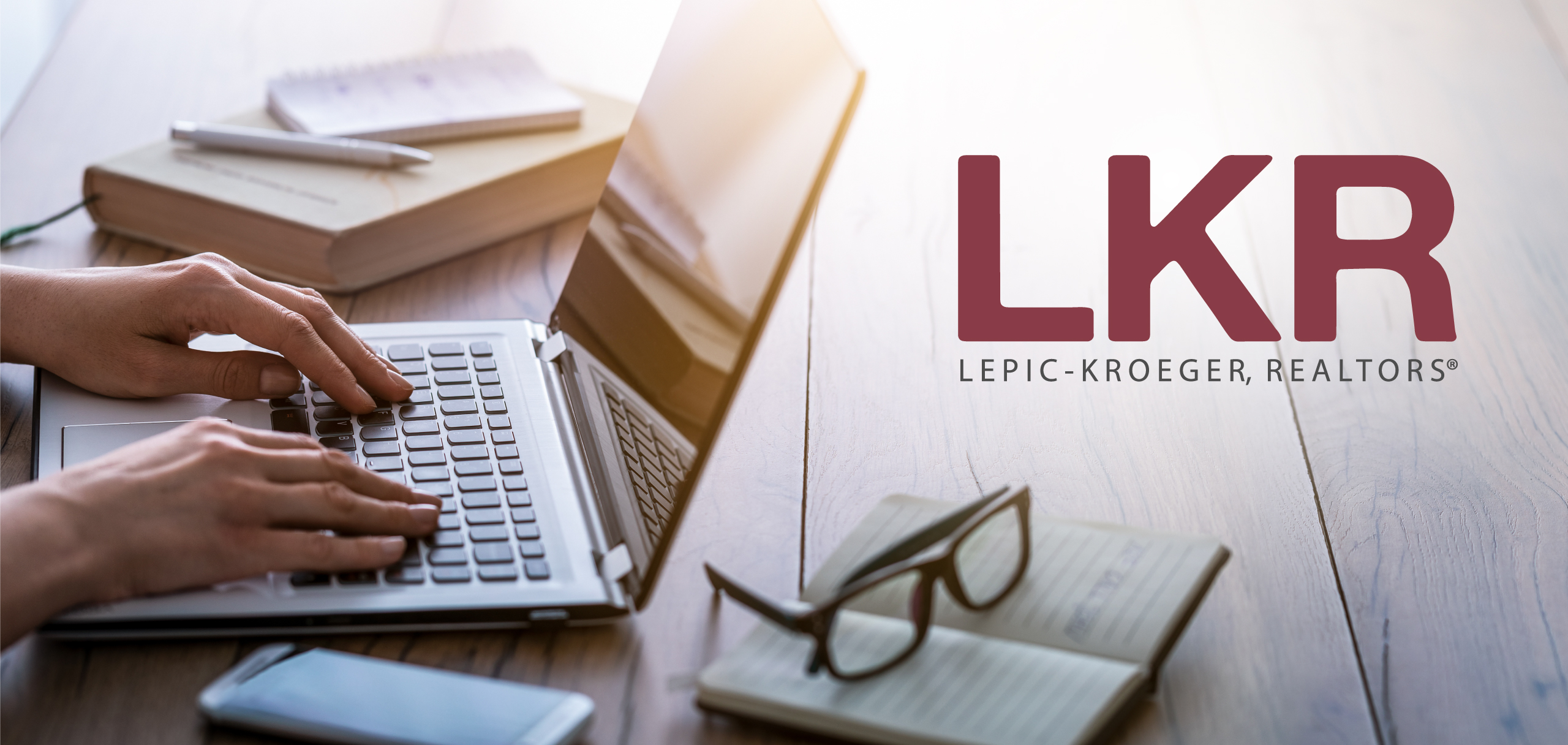 Hands typing on a laptop with the LKR logo