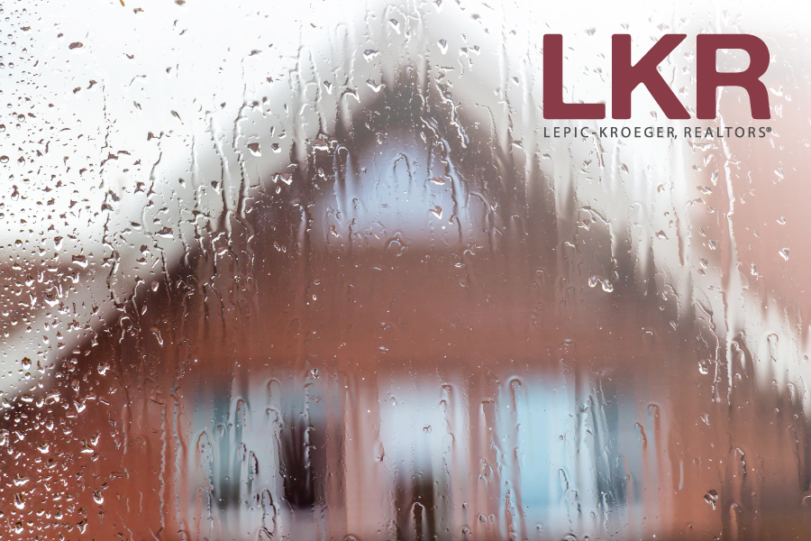 Looking through a raindrop-covered window at a home with the LKR logo